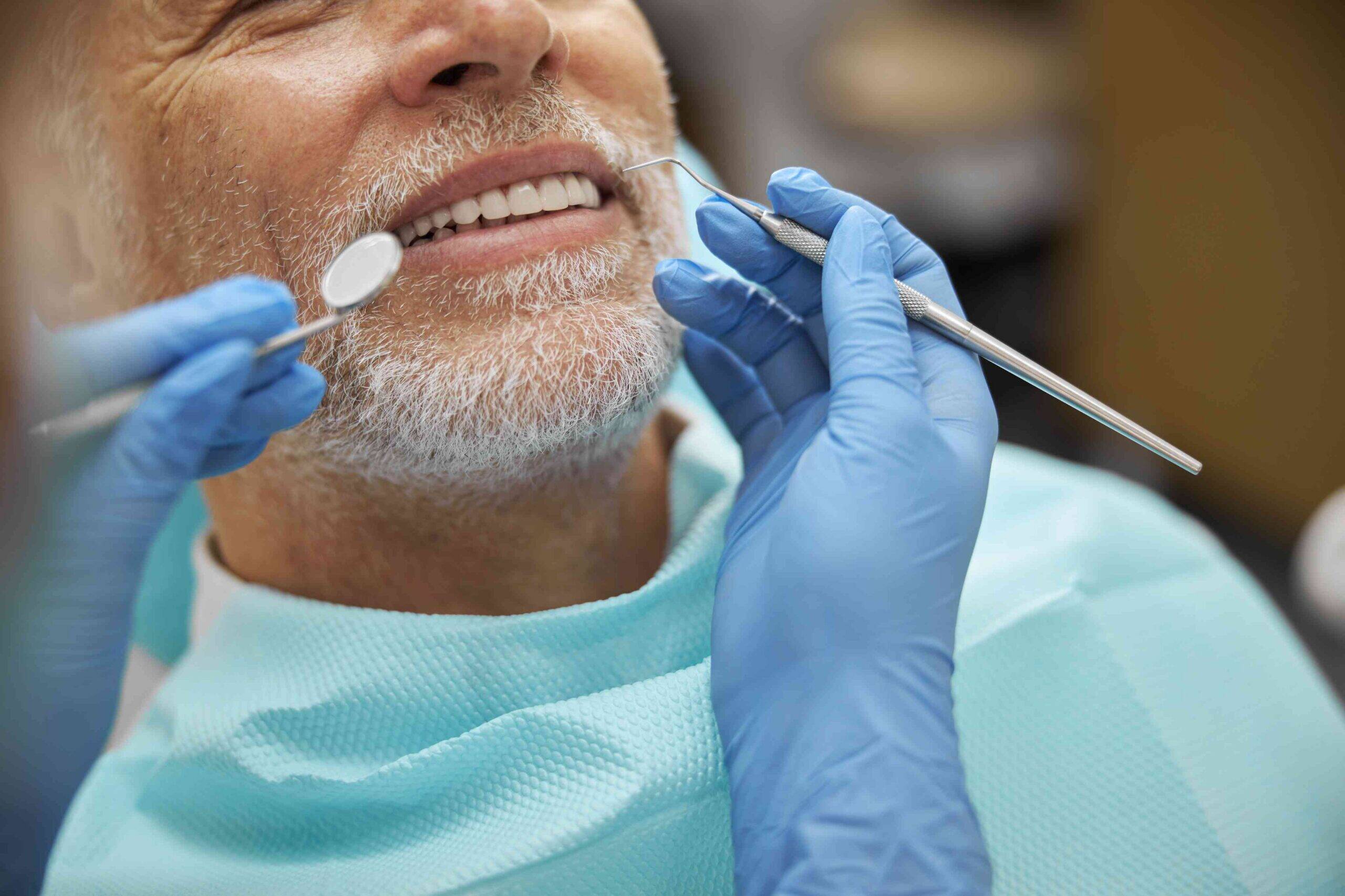 Senior patient receiving a dental checkup with dental tools.