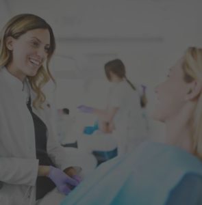 A dentist standing and talking to a seated patient in a dental clinic