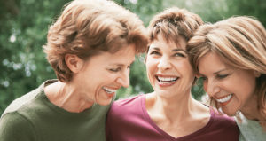 three middle aged women smiling and laughing together