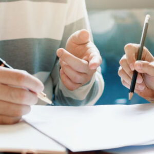 Close up photo of two persons signing documents